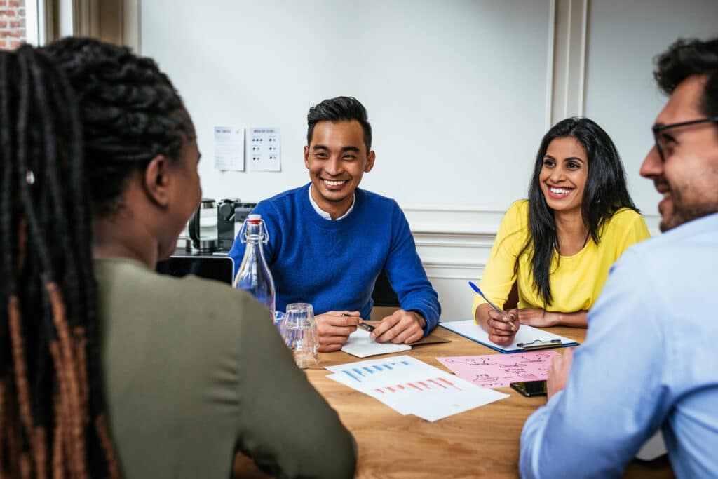 Vier mensen aan een tafel die met elkaar praten