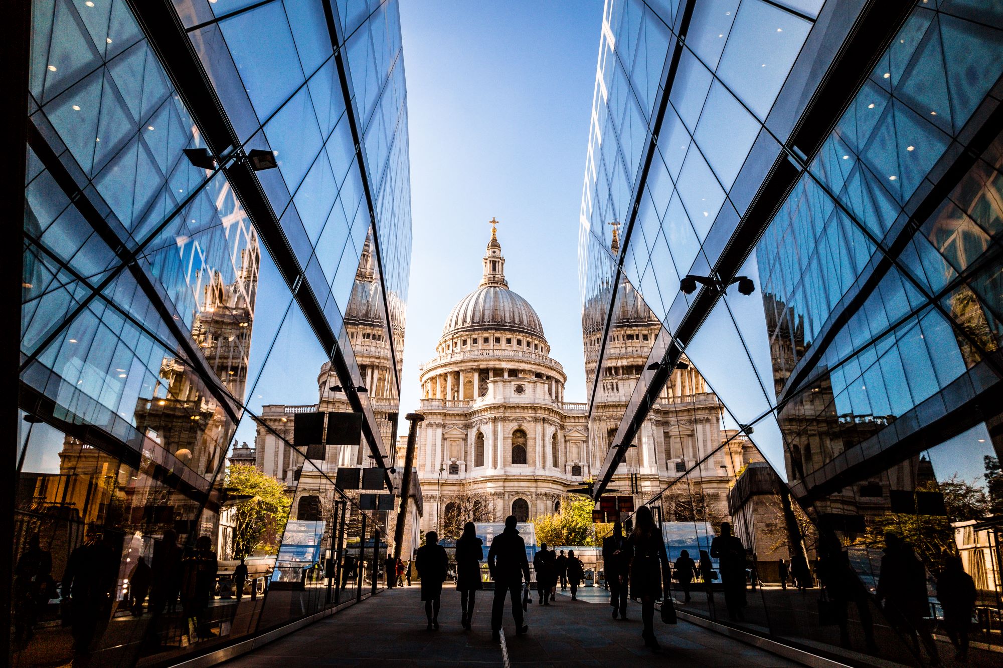 St Paul's through a glass building alleyway against blue sky